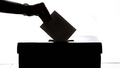 a person is casting a vote into a box
