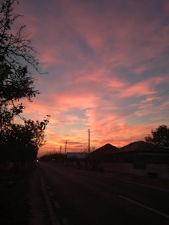 A quiet countryside road bathed in the warm light of a red evening sky.