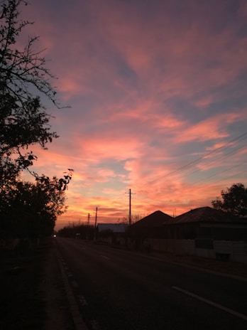 A quiet countryside road bathed in the warm light of a red evening sky.