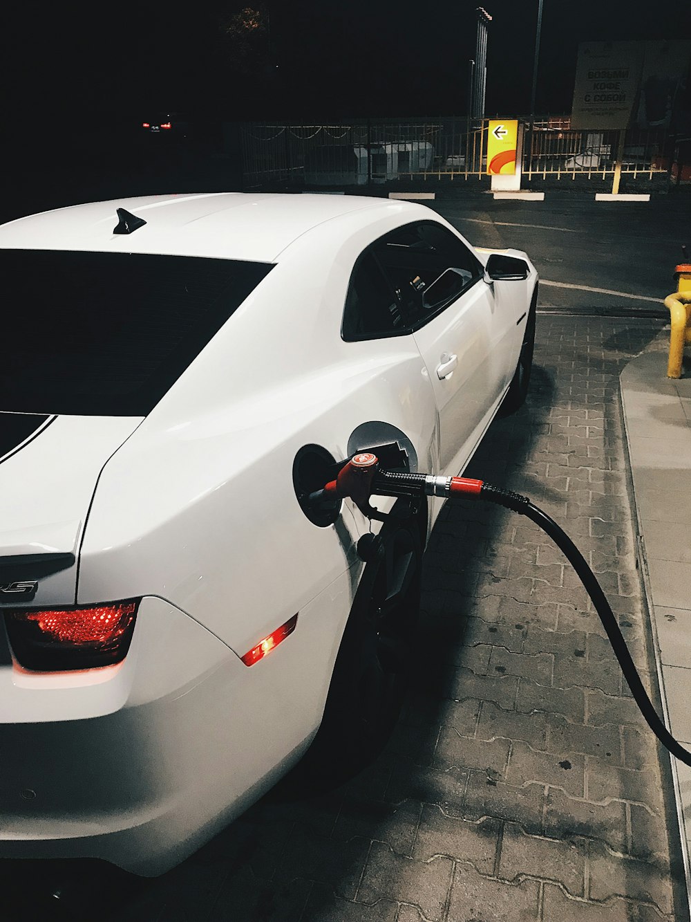 fueling white coupe at night