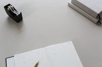 Minimalist workspace featuring a luxury branded agenda and a metallic pen with subtle amber highlights.