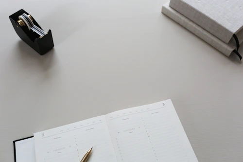 Elegant minimalist office desk with a sleek pen and a closed leather notebook.