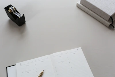 Minimalist workspace featuring a luxury branded agenda and a metallic pen with subtle amber highlights.