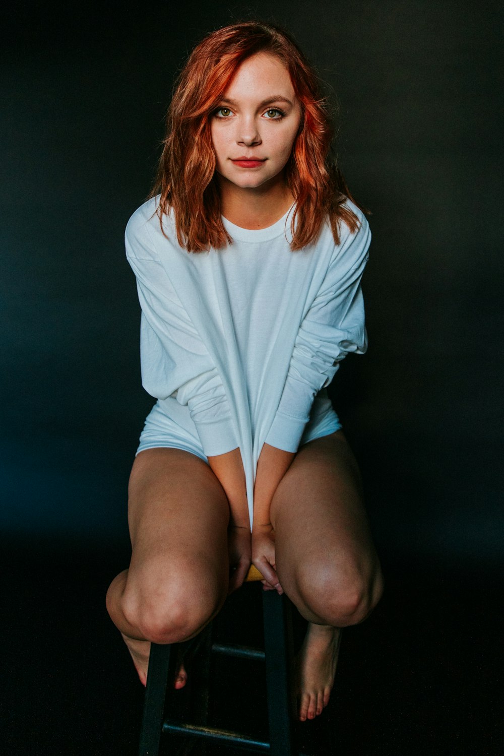 woman wearing white long-sleeved shirt sitting on chair