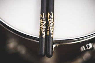 Sleek modern drumsticks resting on a black leather surface.