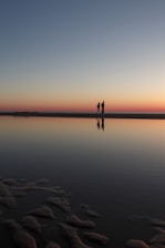 two person standing on beach dock