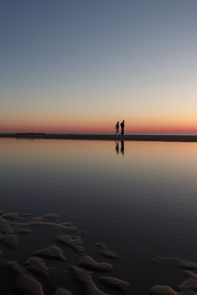 two person standing on beach dock