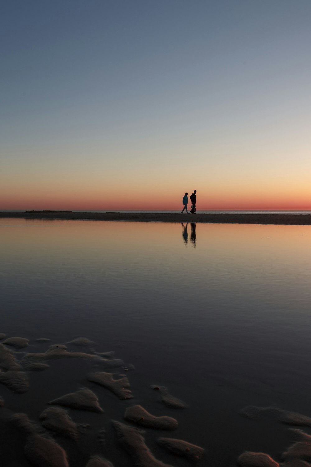 two person standing on beach dock