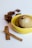 A yellow bowl contains two Chinese tea eggs, one of which is cracked open to reveal its marbled pattern. Star anise and two cinnamon sticks are placed beside the bowl on a light surface.
