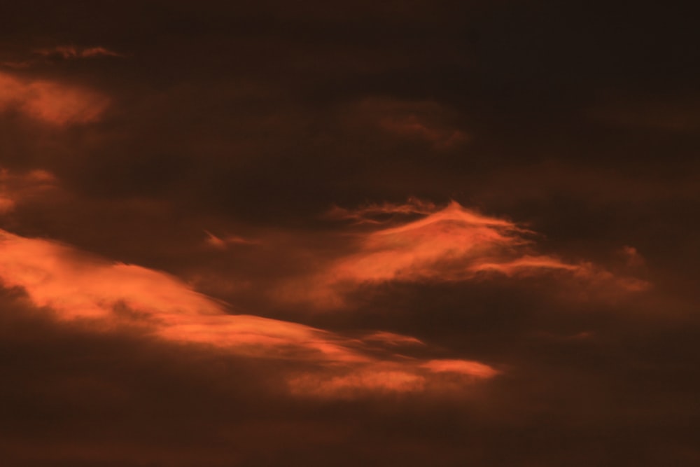 um avião voando em um céu nublado ao pôr do sol