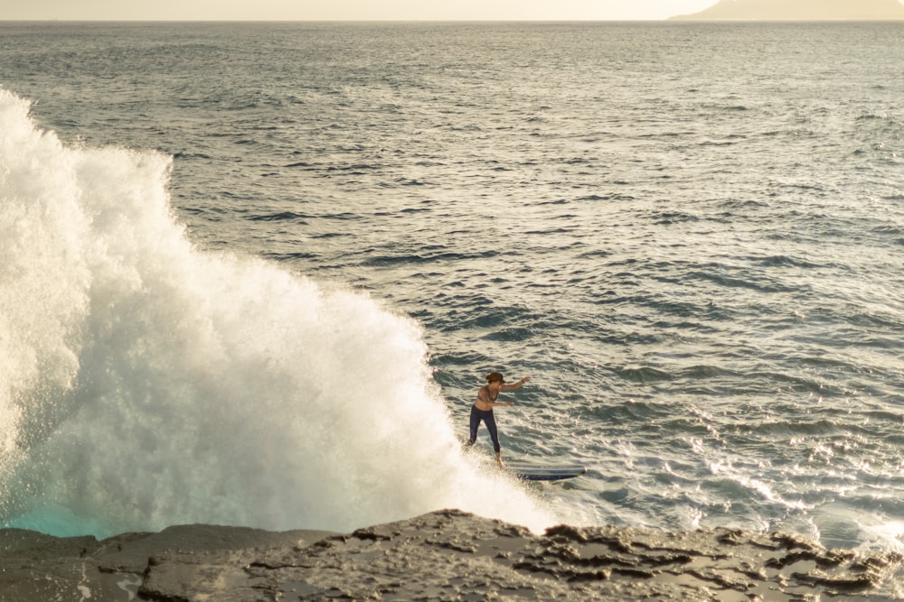 surfer at sea near rocks during daytime