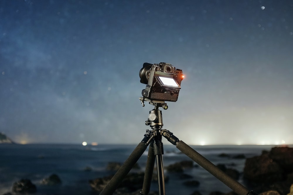 야간에 별을 향하는 삼각대가 있는 카메라