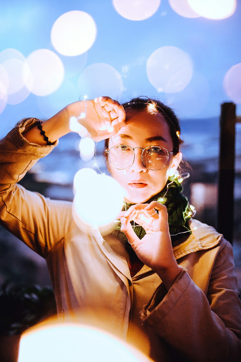 selective focus photography of woman holding string lights