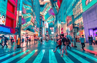 people walking on road near well-lit buildings