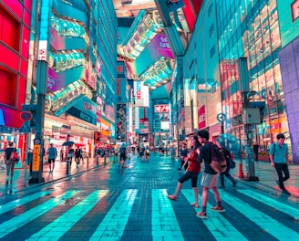 people walking on road near well-lit buildings