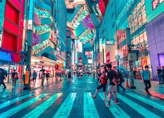 people walking on road near well-lit buildings