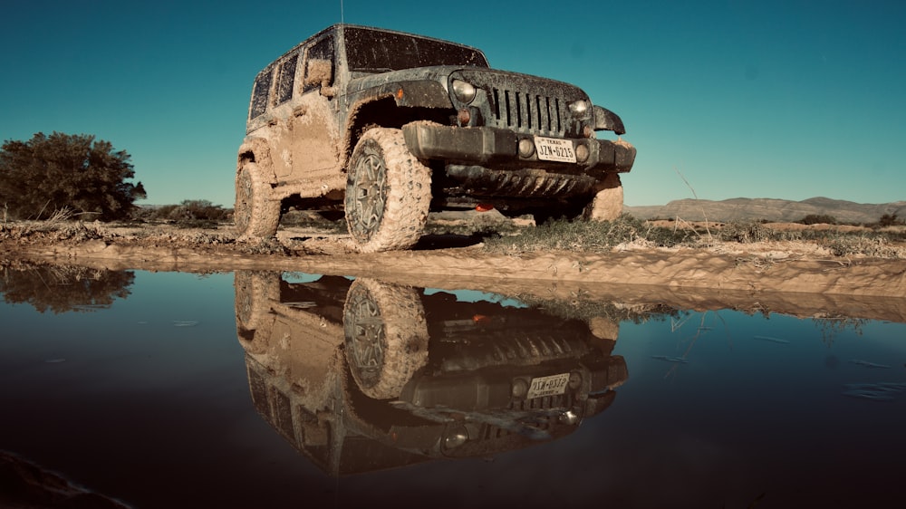 Jeep Wrangler Unlimited SUV preto estacionado perto de corpo d'água sob céu claro durante o dia