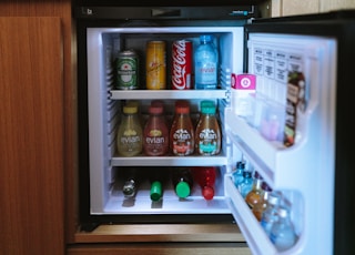 open black compact refrigerator filled with soda bottles