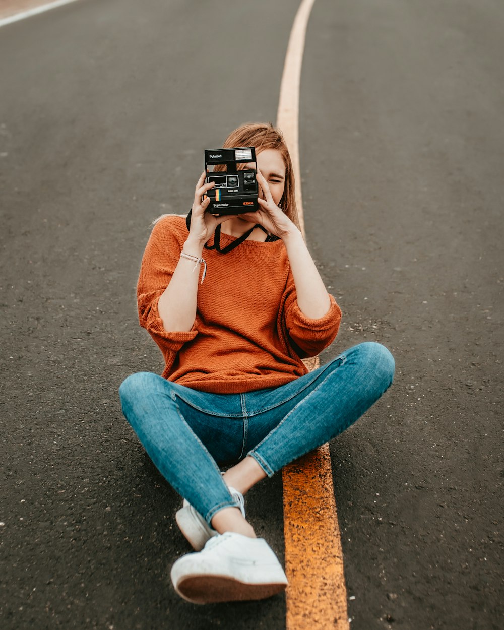 Donna seduta in mezzo alla strada con una macchina fotografica di passo durante il giorno