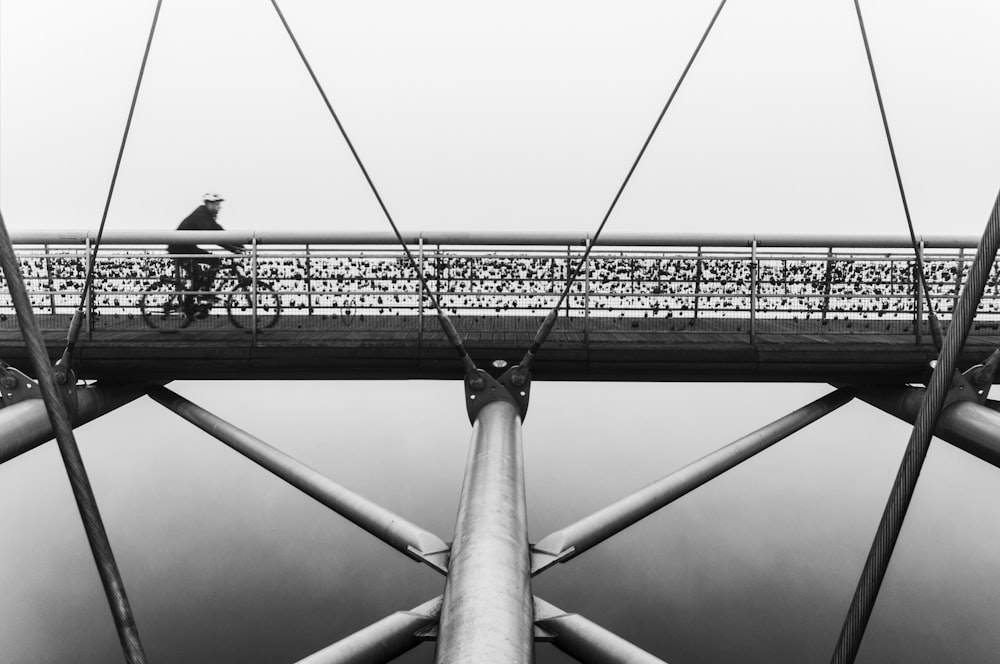 man cycling on suspension bridge