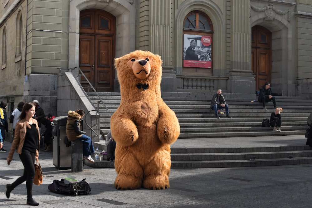 brown bear mascot standing in front of building