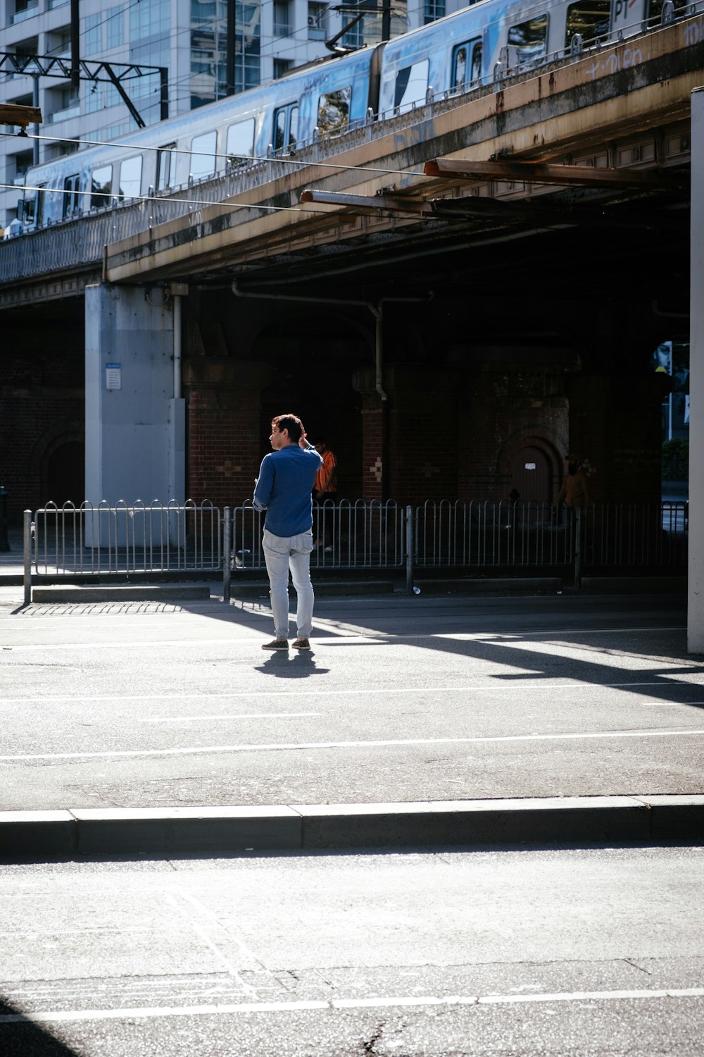 man wearing blue dress shirt standing on road