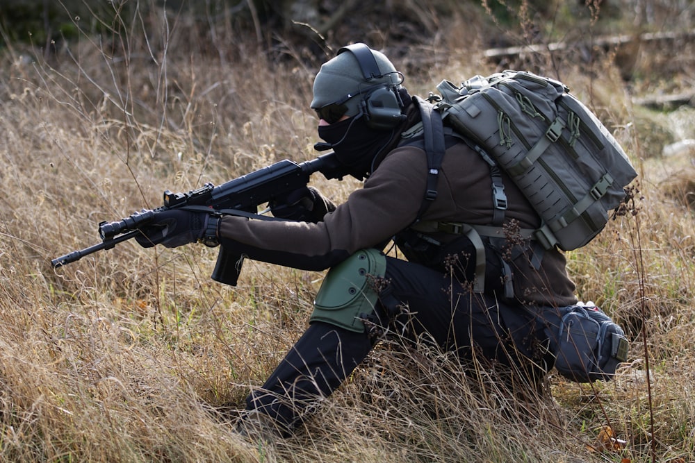 A person in camouflage holding a gun in the woods photo – Free Military  Image on Unsplash