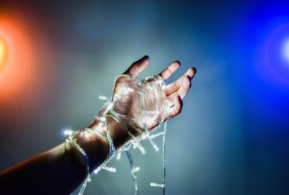 a person's hand holding a string of lights