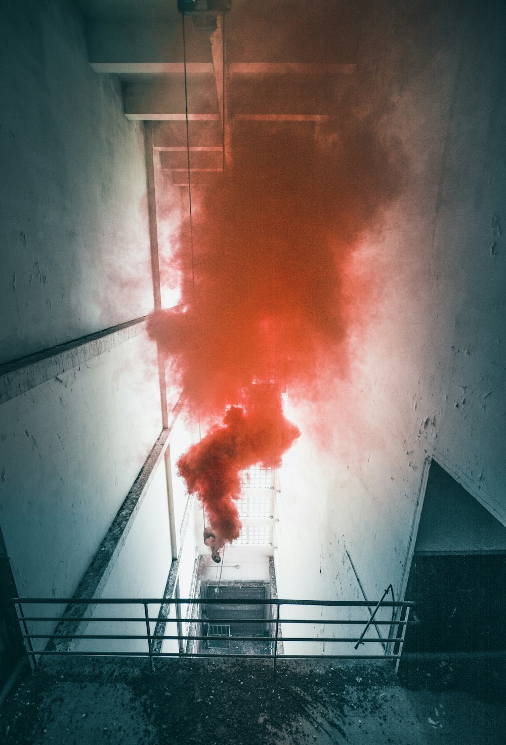 vista angolare bassa dell'uomo spruzza fumi rossi all'interno dell'edificio