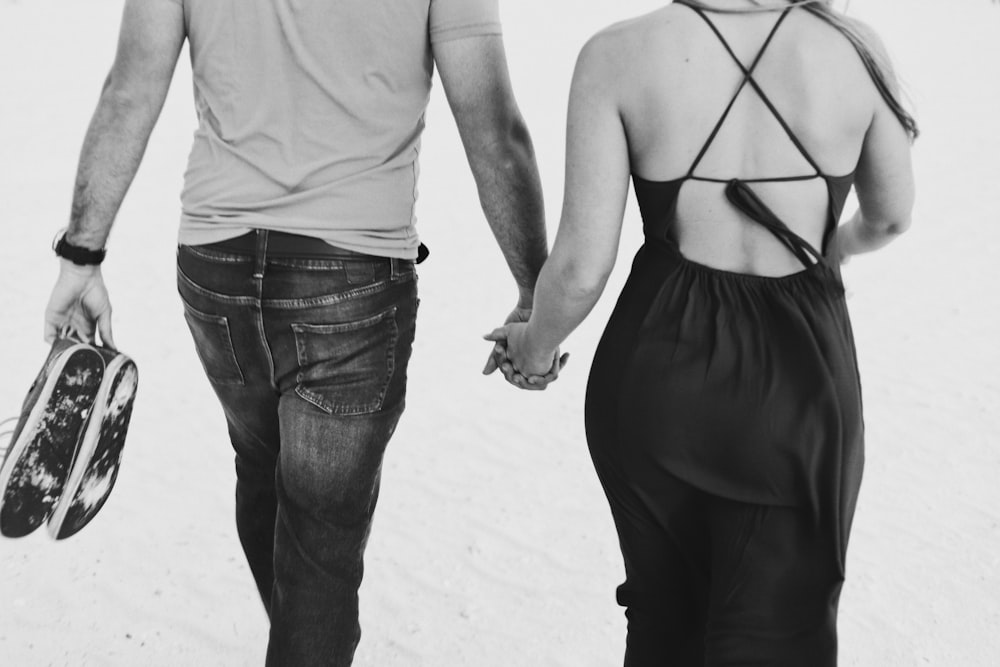 Photo en niveaux de gris d’un homme et d’une femme se tenant la main