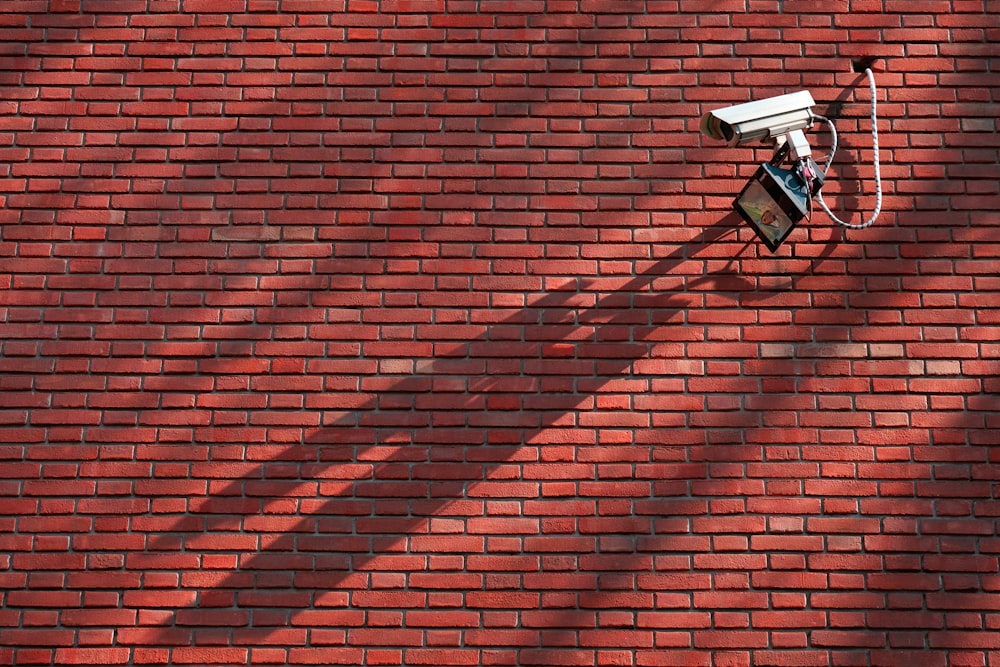 gray CCTV camera beside red bricked wall