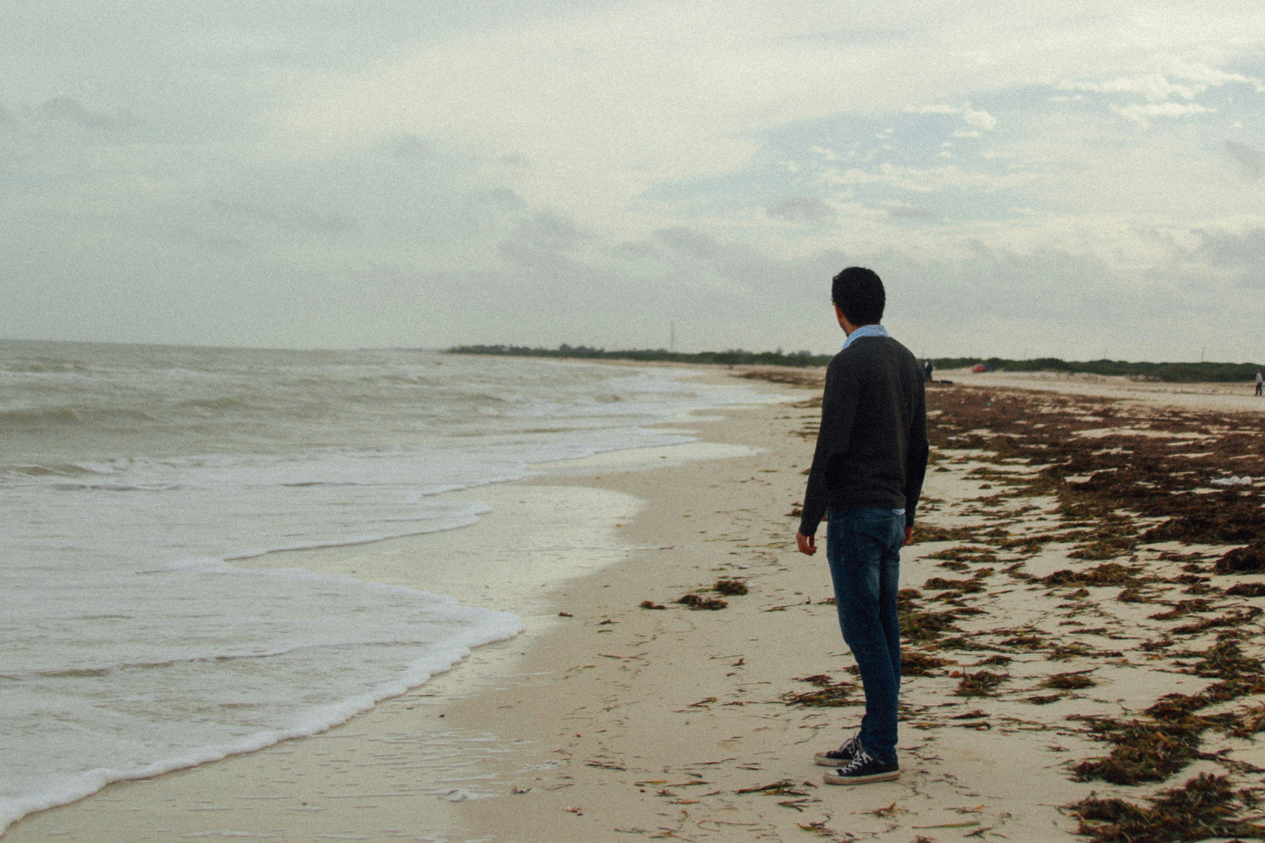 man standing at beach during daytime, man standing in beach during cloudy day