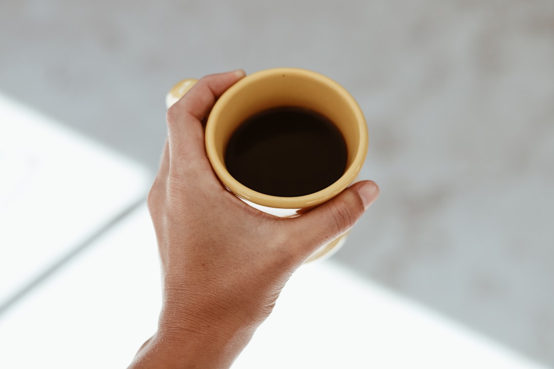 person holding brown ceramic mug