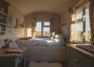 empty bed beside windows during daytime