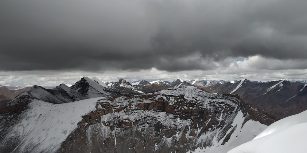 snow-covered mountain under gray clouds during daytime