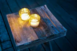Handcrafted beeswax candles glowing warmly on a rustic wooden table.