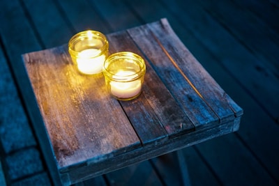 Handcrafted aromatic candles glowing warmly on a rustic wooden table.