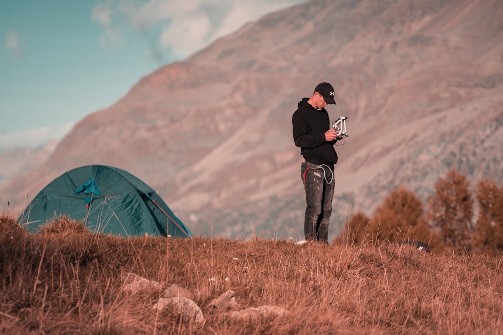 man standing near blue camping tent