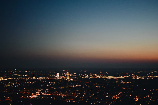 A vibrant city skyline at dusk, lights beginning to twinkle.
