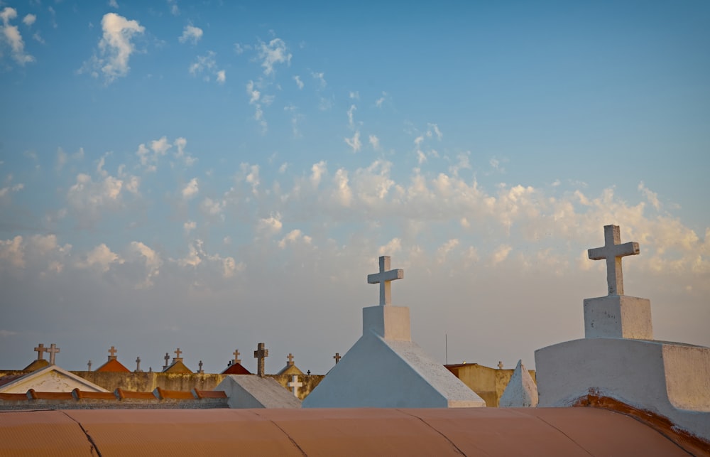 concrete crosses on top of buildings under white clouds and blue sky during daytime