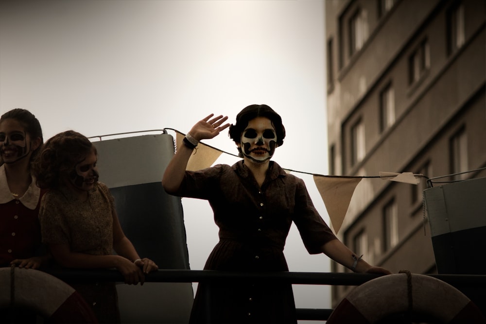 three women with face paint near building during day