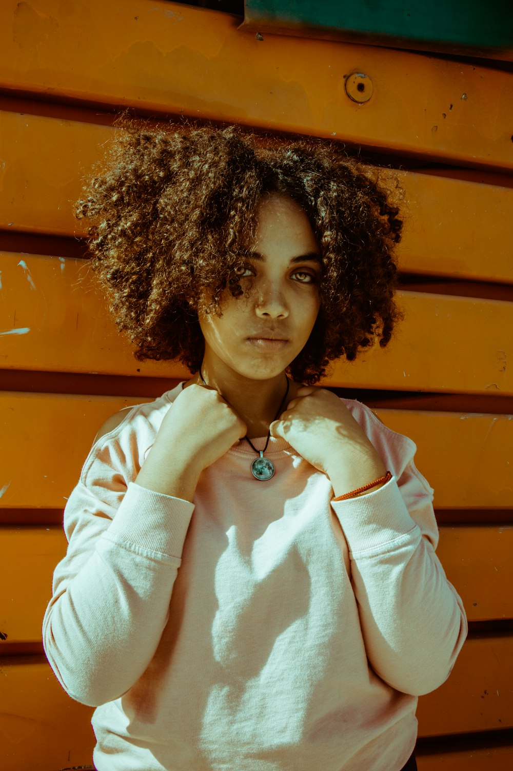 Mulher na camisa cor-de-rosa que está perto do aço amarelo