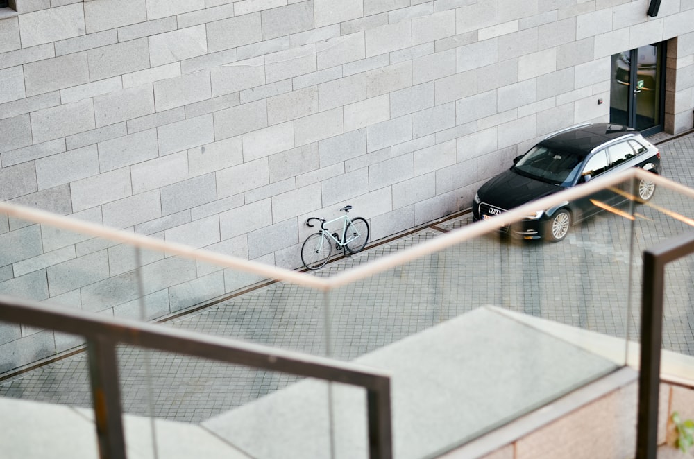 mountain bike leaning on wall front of car near door