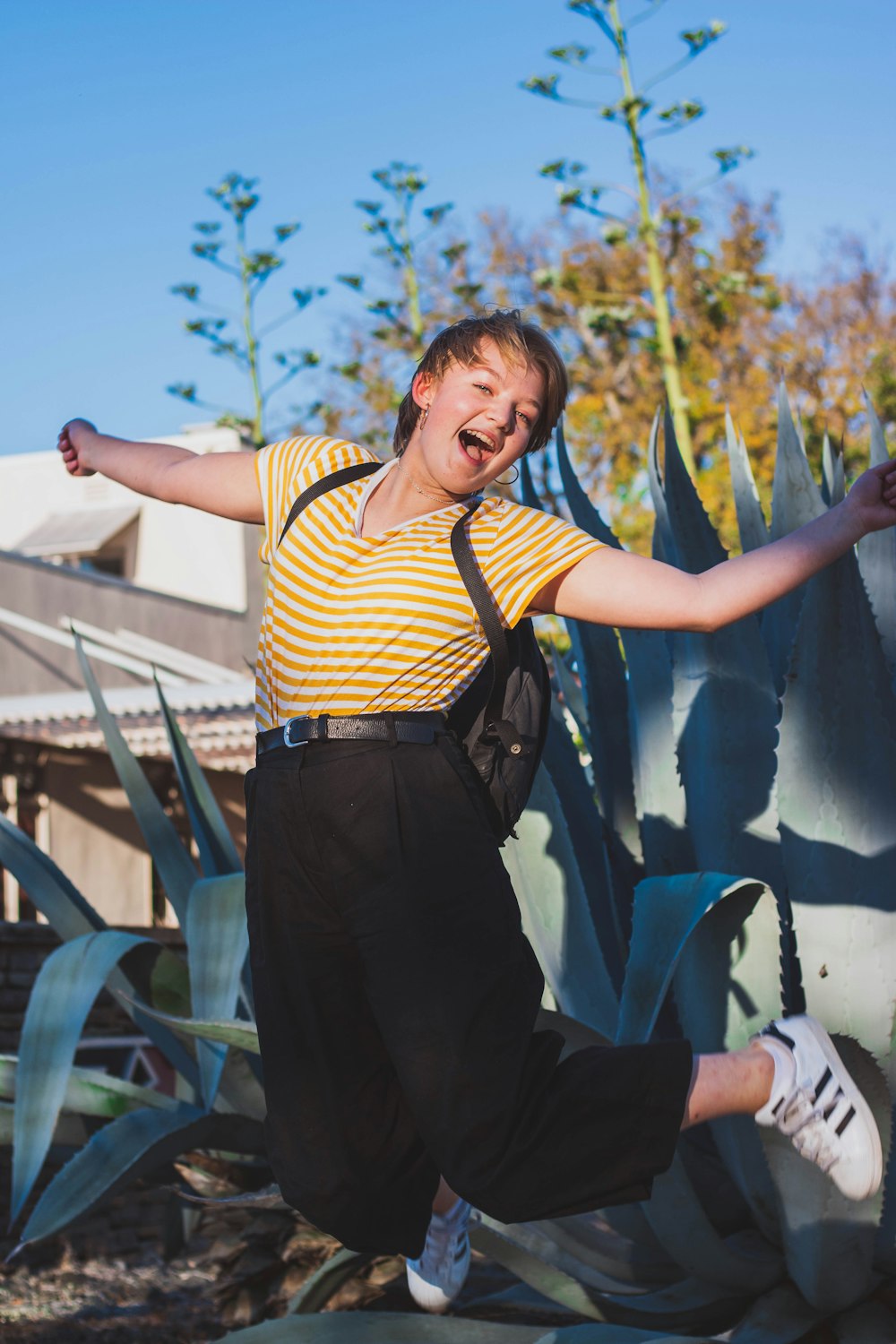 woman wearing yellow-and-white striped blouse jumping mid air