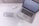 A laptop is placed on a white desk displaying a logo for 'Sparkling Marketing'. Beside the laptop, a glass jar lies on its side with its contents—numerous small, clear beads—spilled across the surface. Nearby, a pen with a decorative gem sits on some business cards, contributing to a coordinated and stylish workspace aesthetic.