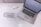 A laptop is placed on a white desk displaying a logo for 'Sparkling Marketing'. Beside the laptop, a glass jar lies on its side with its contents—numerous small, clear beads—spilled across the surface. Nearby, a pen with a decorative gem sits on some business cards, contributing to a coordinated and stylish workspace aesthetic.