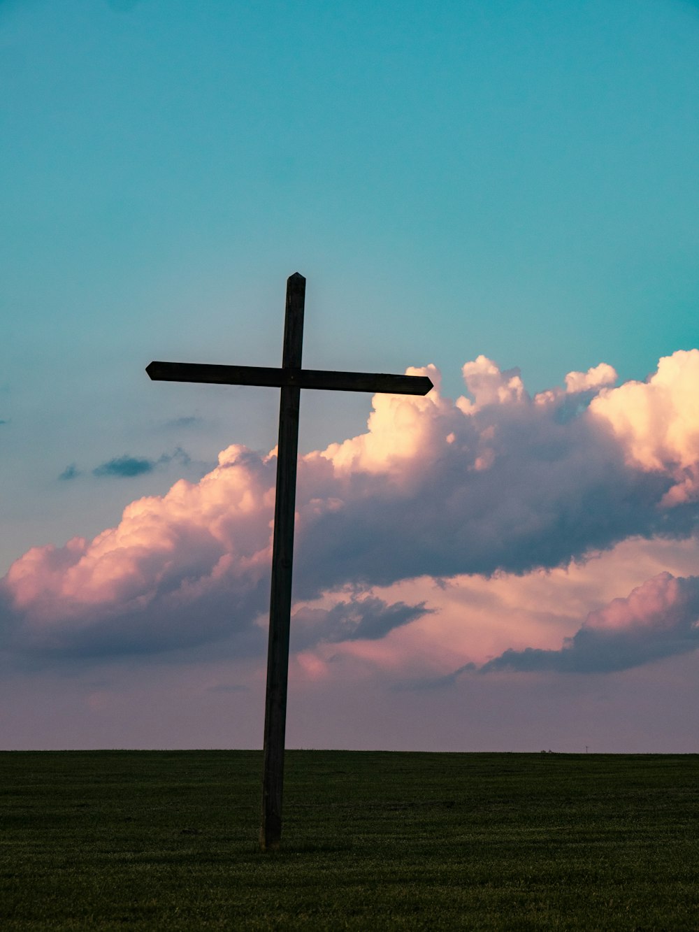 Croce sul campo d'erba sotto il cielo sereno