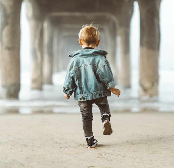 walking boy wearing blue denim jacket under the bridge