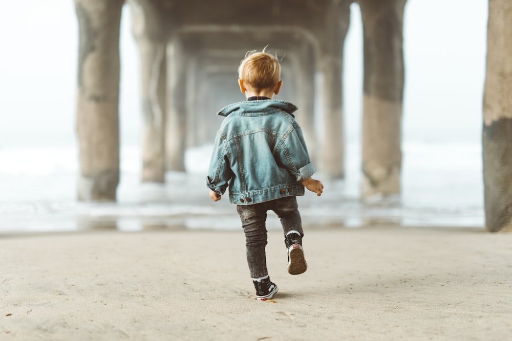 walking boy wearing blue denim jacket under the bridge