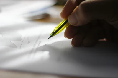 Professional hand holding a golden pen ready to write, with blurred legal statutes in background.